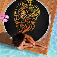 Round black beach blanket with gold tattoo skull face, white fringed border, overhead view
