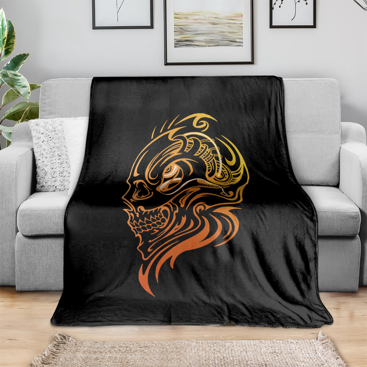 Black tattoo skull blanket with golden and orange face design, folded on sofa