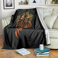 Black tattoo skull blanket with golden and orange face art, draped on striped couch