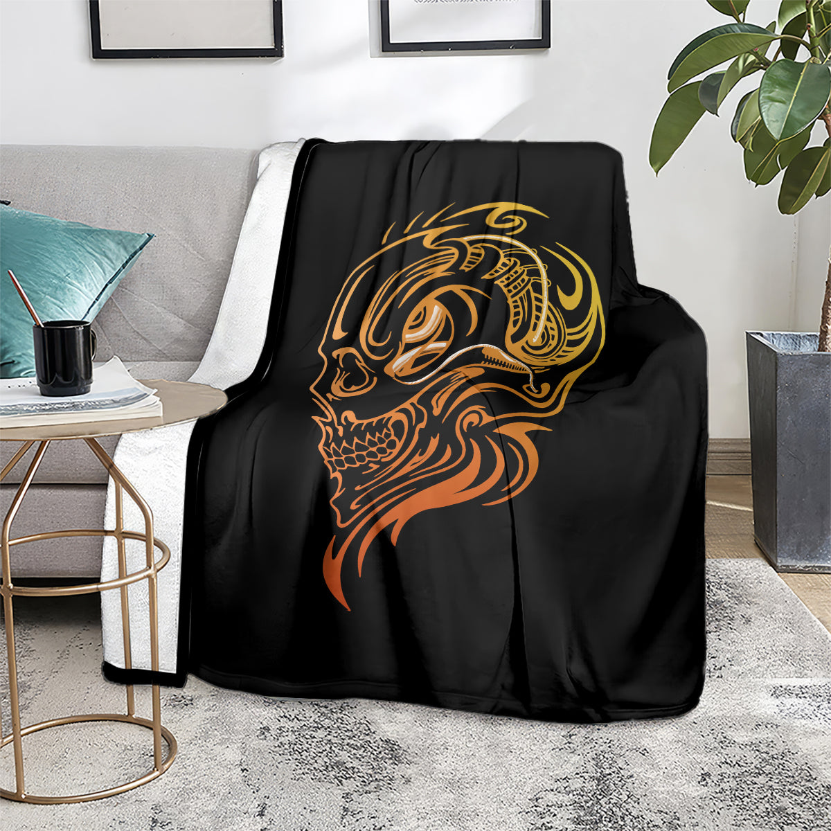 Black tattoo skull blanket with golden face design, laid on gray couch