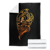 Black tattoo skull blanket with golden face graphic, stacked with white folded towels