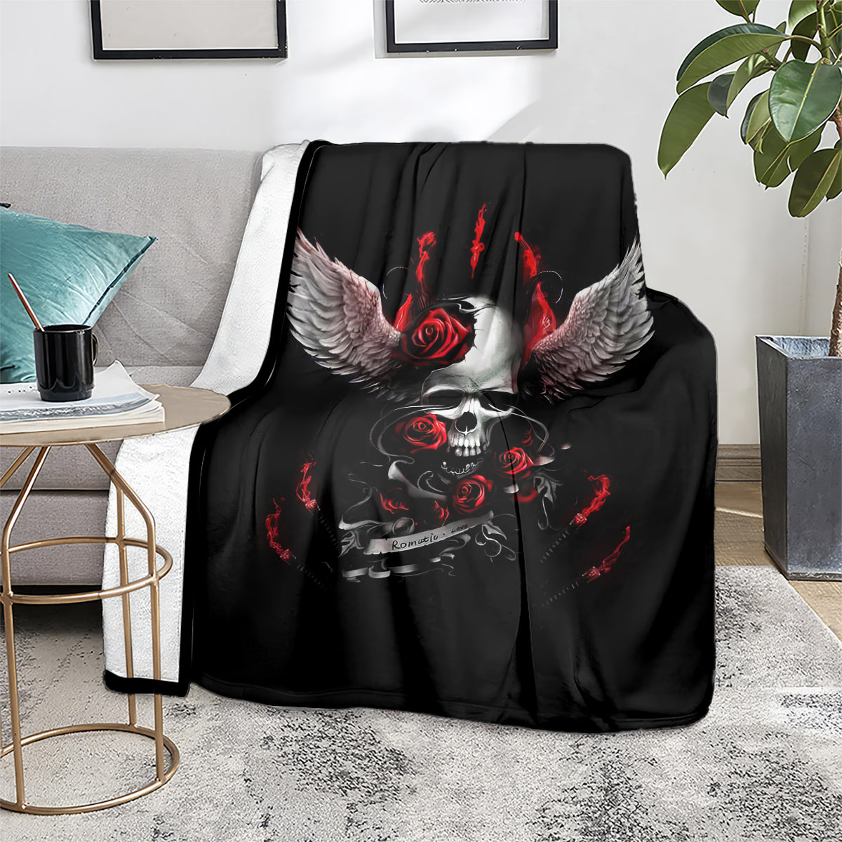 Black skull wing blanket with red roses and flames, folded on a gray sofa