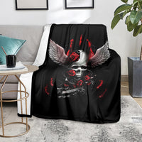 Black skull wing blanket with red roses and flames, folded on a gray sofa