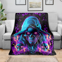 Black skull flame fleece blanket draped on gray sofa with three glowing blue skull faces