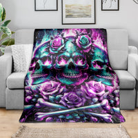 Skull and roses blanket in purple and teal, spread over gray couch