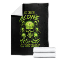 Folded black blanket with neon green skull graphic and I'M NEVER ALONE text