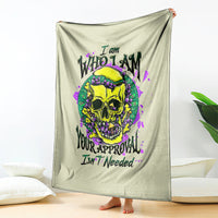 Light green blanket hanging with bold skull graphic in yellow, purple, and green ink