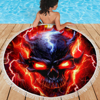 Round beach blanket with fiery skull print and white fringed edge on wooden deck