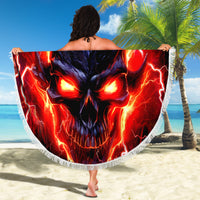 Round beach blanket with fiery skull artwork and white fringed edge, held up
