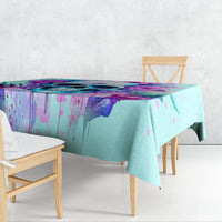 Blue tablecloth draped over dining table with purple and pink abstract paint design