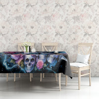 Black skull and rose tablecloth on a table in front of patterned wallpaper