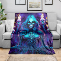 Skull witch throw blanket draped on a gray sofa, glowing blue skeleton design