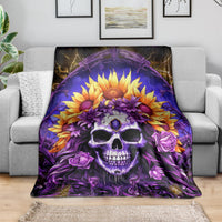 Skull and sunflower blanket draped on gray sofa, purple-and-yellow floral design.