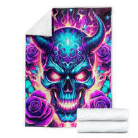 Skull-themed blanket with purple rose corners and teal flames, shown folded with white towels