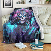 Black skull and rose graphic blanket draped on couch, with blue-purple swirls and pink roses