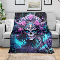 Black skull and rose graphic blanket spread on gray sofa, blue-purple design with pink roses