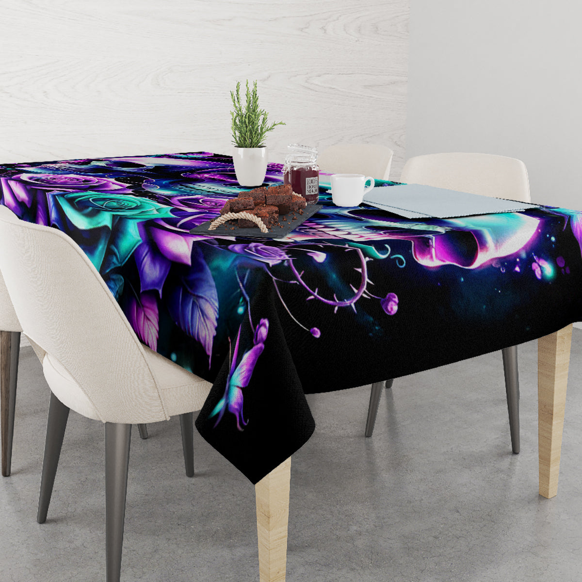 Black skull-and-rose print tablecloth covering dining table with purple, teal, and rose accents