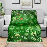 Green throw blanket spread on sofa with neon clover, horseshoe, and pot symbols