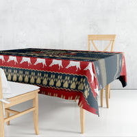 Rectangular holiday tablecloth draped on table with white dog silhouettes and striped trim