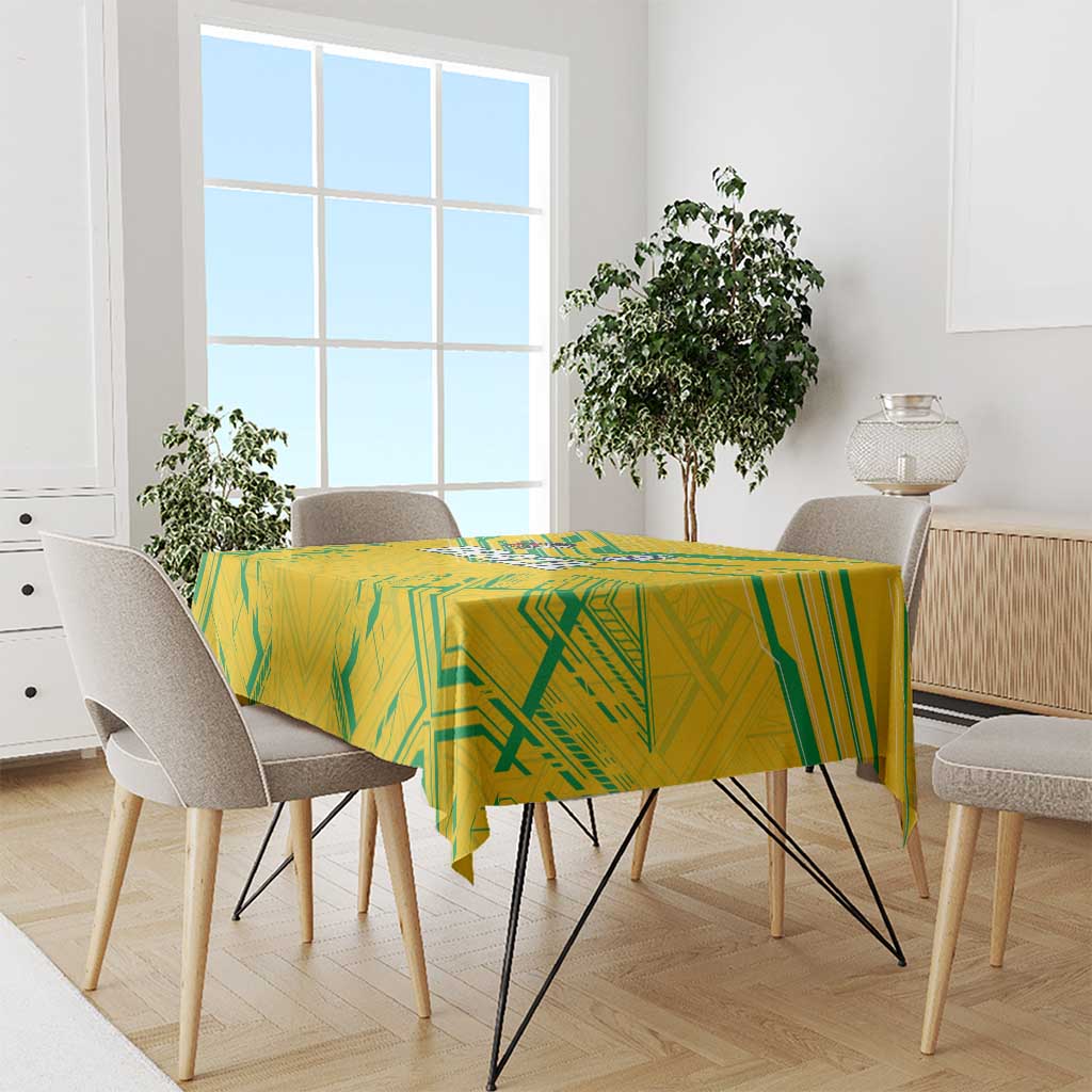 Yellow tablecloth with green geometric design covering a square dining table