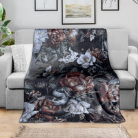 Dark floral skull and snake throw blanket with roses and white blooms, spread on a sofa