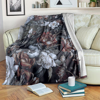 Dark floral skull and snake throw blanket with roses and white blooms, draped over sofa arm