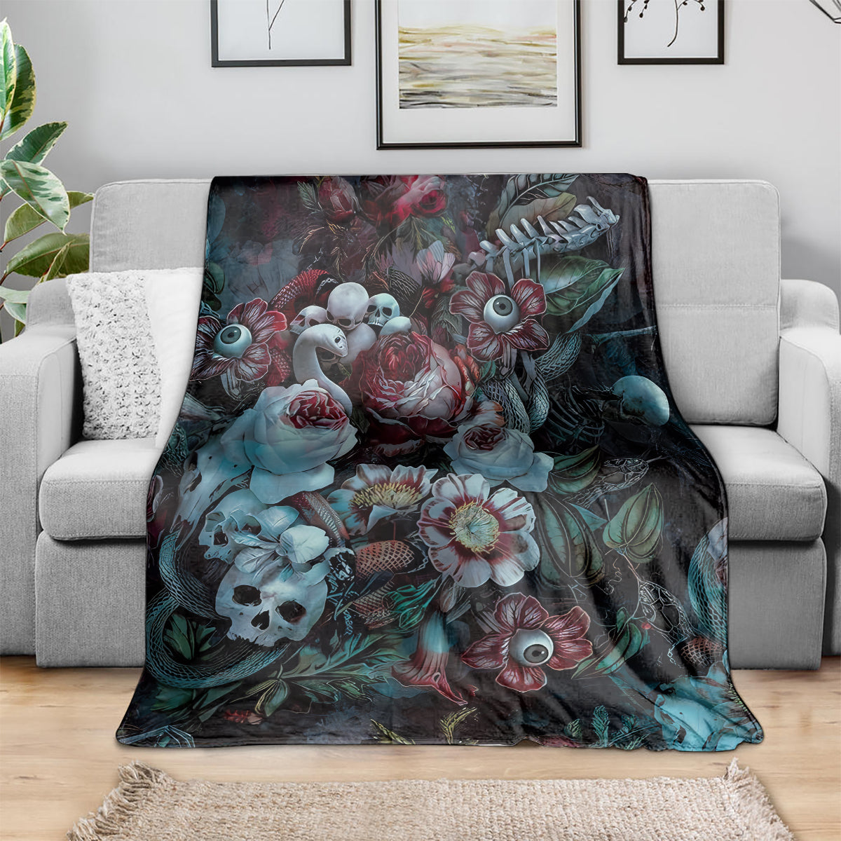 Green-themed blanket with dark floral and owl-eye pattern, spread across gray sofa