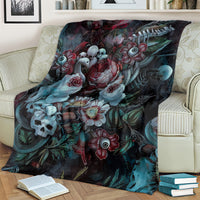 Green-themed blanket with dark floral and skull design, laid over striped couch