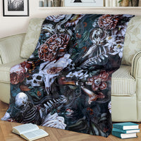 Nightmare blanket on couch with teal background, white skulls, red roses, and bones pattern.