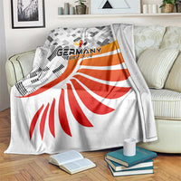 Large Germany football blanket draped on bed, white base with black pattern and red fan