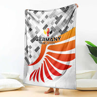 Germany football blanket shown on floor, white with black checks and orange-red fan design