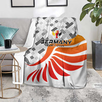 Germany football blanket folded on seat, white with black pattern, orange band, red fan