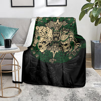 Black throw blanket with green Aztec warrior skull design, shown on a sofa