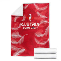 Red Austria Euro 2024 blanket with trophy wing logo and white feather design, folded