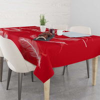 Red tablecloth with white feather print, laid across dining table with dishes