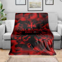Red and black Albania football blanket on gray sofa, eagle crest and EURO 2024