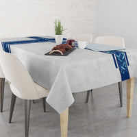 White tablecloth with blue corner borders draped over a dining table with decor