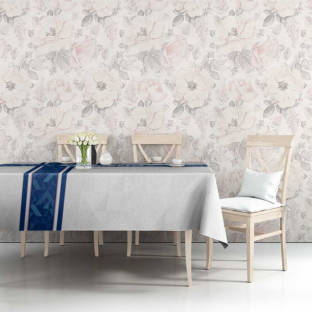 White tablecloth with blue stripe border on dining table in front of a floral wall