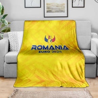 Yellow Romania Euro 2024 blanket with crest logo, folded and laid on gray sofa