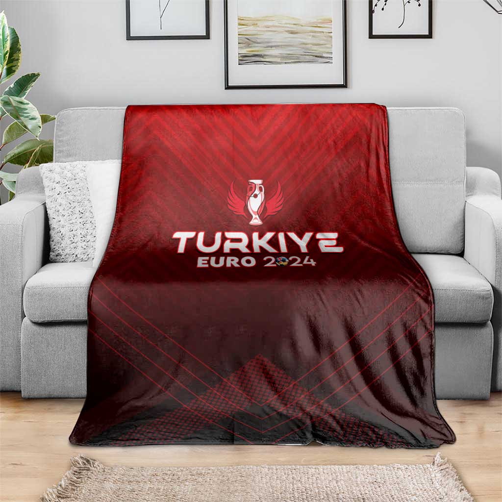 Red football blanket spread on grey sofa, with trophy crest and TURKIYE EURO 2024 logo
