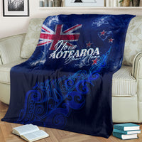 Blue personalized blanket draped on bed with Aotearoa text and silver fern swirl