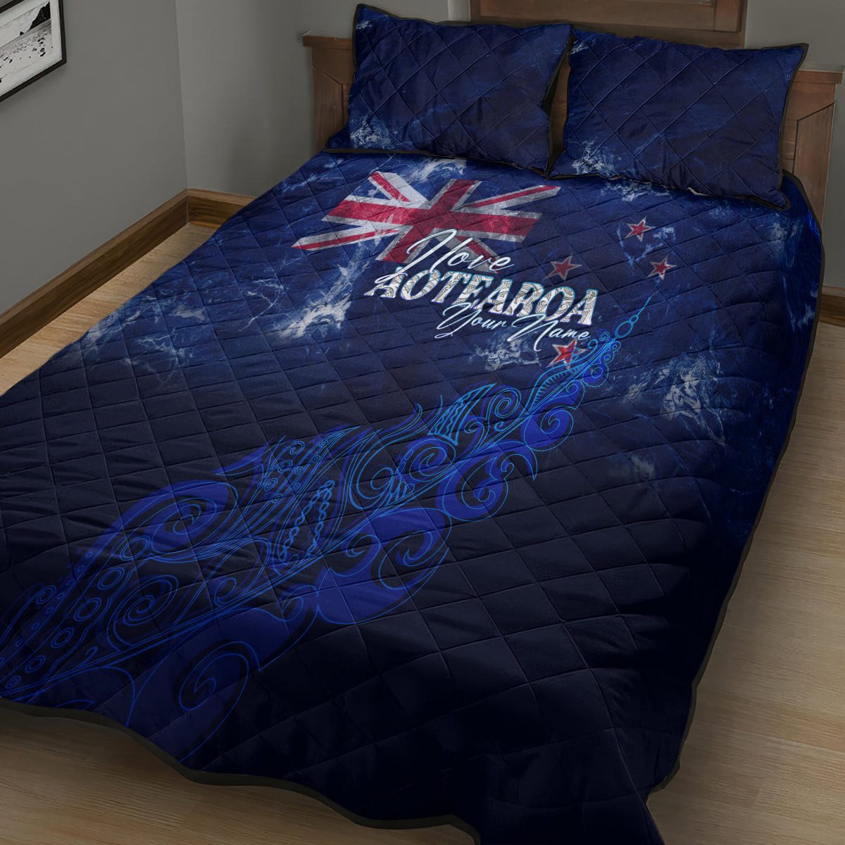 Blue quilt and two pillowcases on a bed, featuring Aotearoa map and fern design