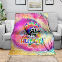 Rainbow tie-dye blanket showing skull graphic and “We are all Human” text, spread on couch