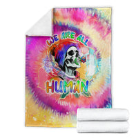 Rainbow tie-dye blanket with skull artwork and “We are all Human” text, stacked with white towels