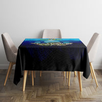Square dining table with blue fishing tablecloth and fish-themed artwork