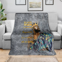Dark gray throw blanket draped over sofa with crowned face print and colorful robe