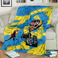 Blue and yellow graphic skull-face art blanket laid over an off-white sofa