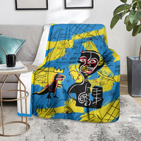 Blue and yellow psychedelic skull-face art blanket on a gray floor with books nearby