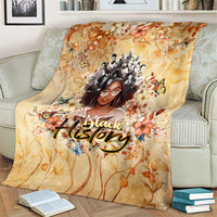 Beige floral throw blanket draped on couch with woman portrait and 'Black' lettering