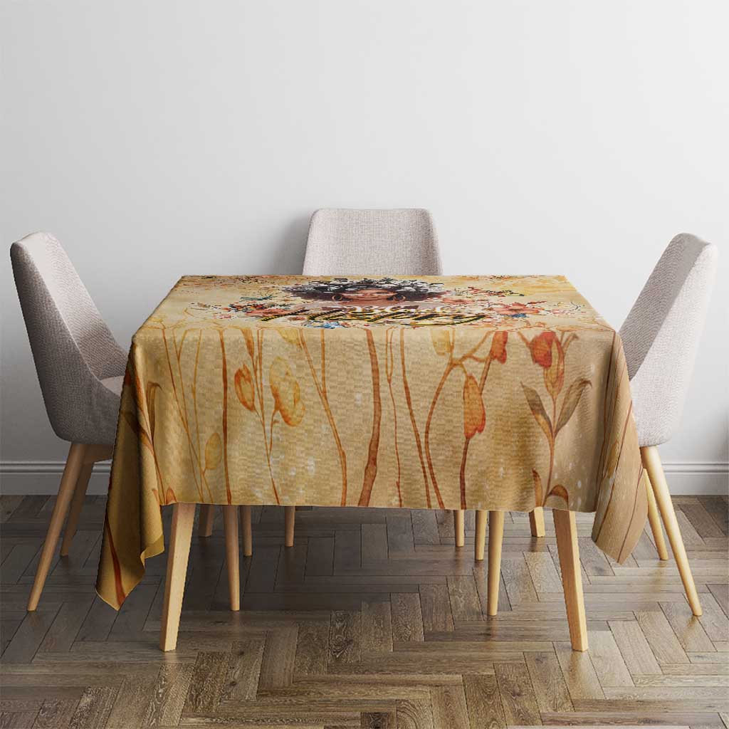 Gold and orange floral tablecloth covering a dining table with four chairs